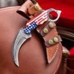A 7.5-inch handmade Damascus steel karambit knife by BCK, featuring an American flag-designed handle and a leather sheath.