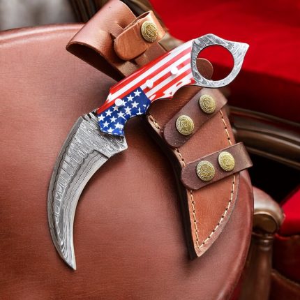A 7.5-inch handmade Damascus steel karambit knife by BCK, featuring an American flag-designed handle and a leather sheath.